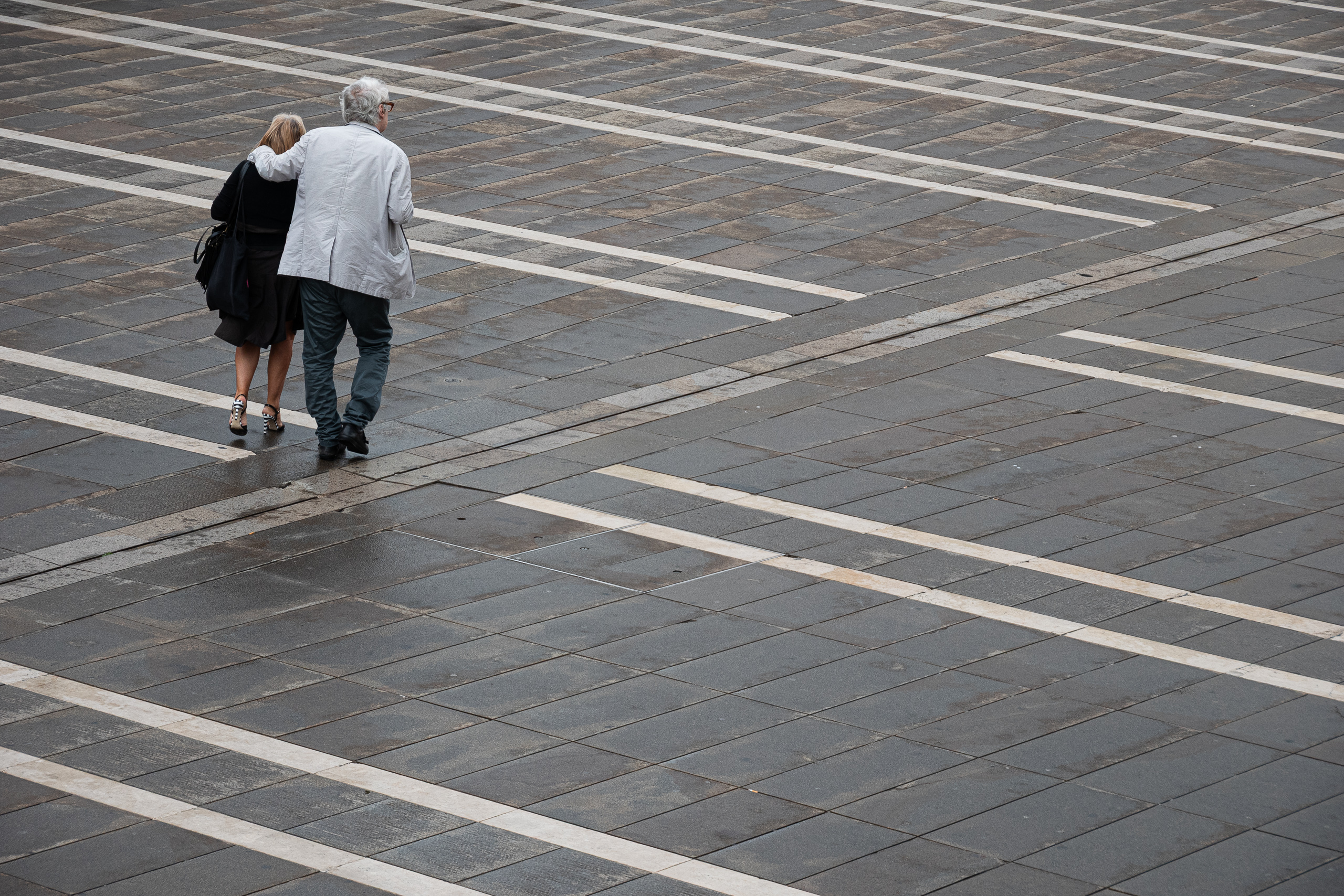 Ein Paar überquert das gestreifte Pflaster der Piazza